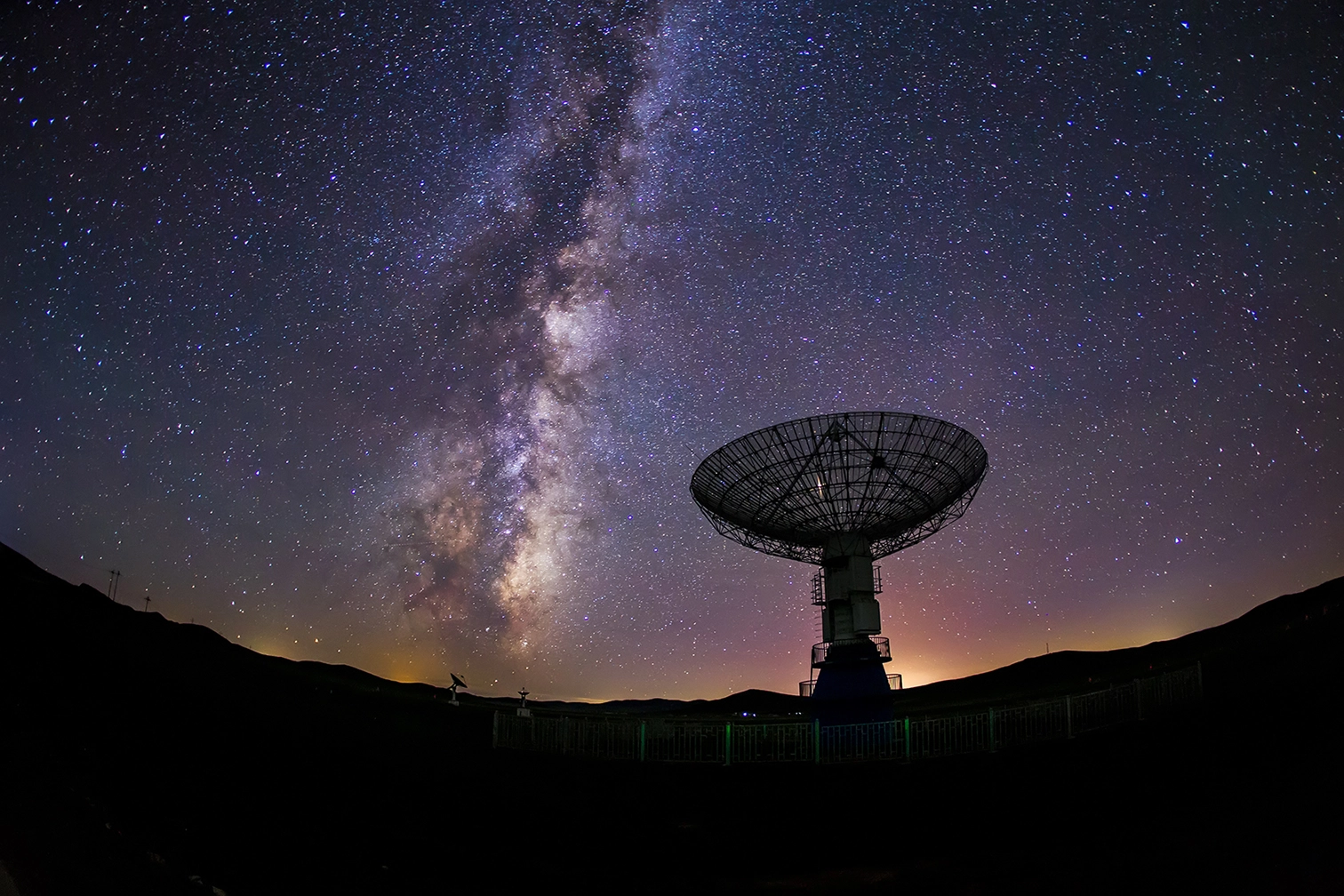 Radio telescope under a starry Milky Way sky.