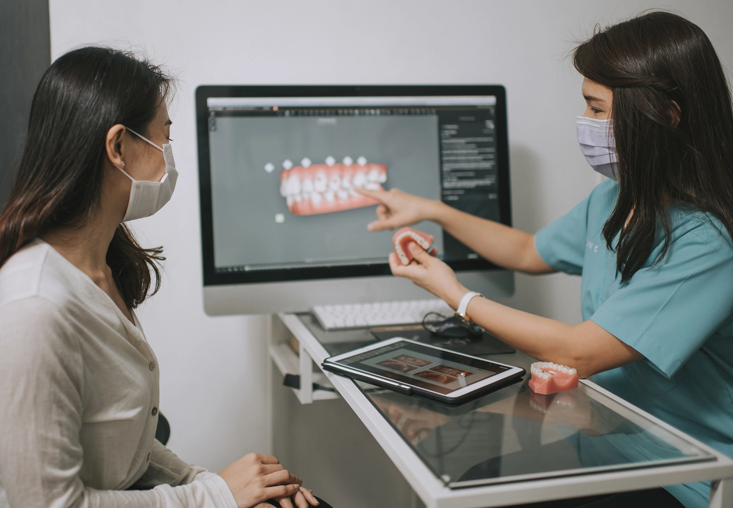 Dentist showing a patient a digital teeth model on a monitor.